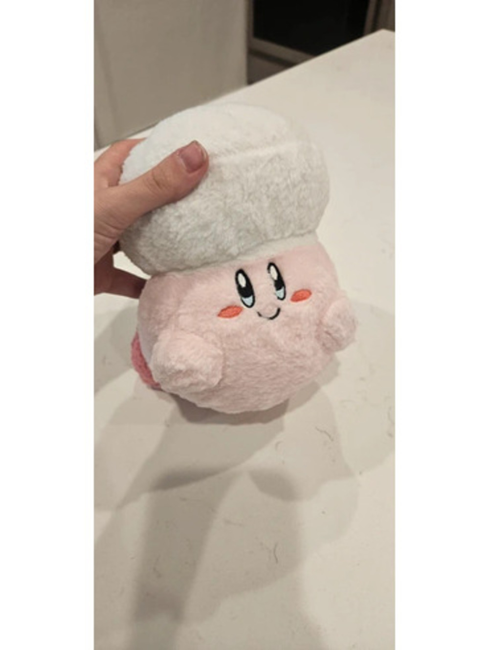Large fluffy pink Kirby plush toy wearing a white chef or mushroom-like hat